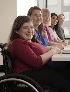 A group of people smile as they work together in an office